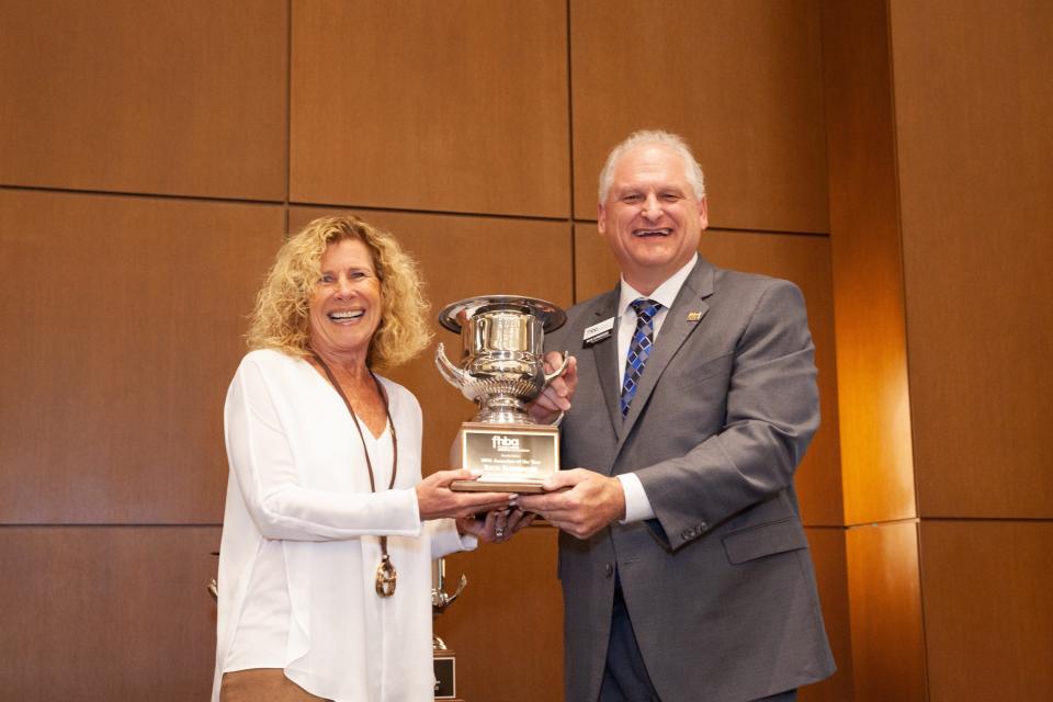 Rick Ilmberger is presented the 2021 FHBA Associate of the Year cup by Robyn Bonaquist, of B2 Advertising.