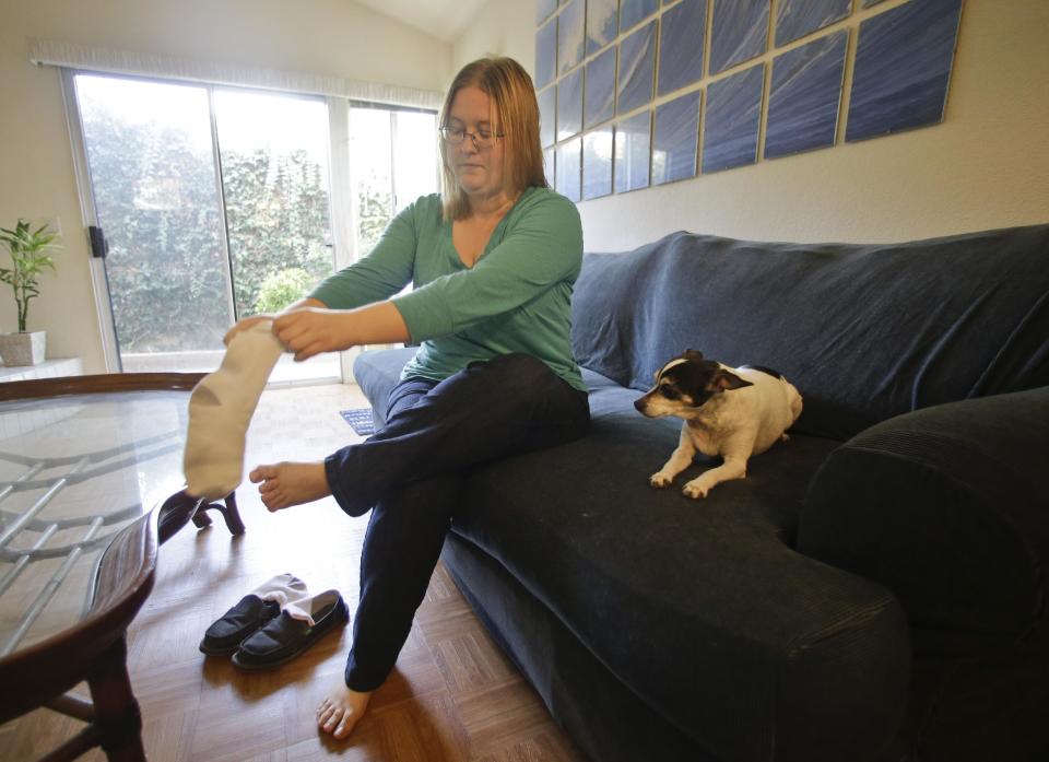 In this Tuesday, Jan. 29, 2013 photo, Meliisa Duffy prepares to leave for work as her dog, a pure bred rat terrier named Dinky, anxiously watches her put on her socks and shoes in Carlsbad, Calif. "She starts to get anxious when I am getting ready to go out, whining, pacing, shivering," Duffy says. Being left with a food-dispensing toy calms her reaction to Duffy's departure and has longer-lasting effects as well. (AP Photo/Lenny Ignelzi)