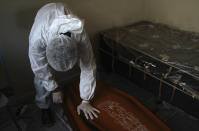 FILE - In this Jan. 22, 2021, file photo, a public funeral service worker helps to remove the body of Jose Bernardino Ferreira, 77, who died from complications related to COVID-19 in his home, in Manaus, Amazonas state. Brazil’s COVID-19 death toll, at nearly 250,000 on Thursday, Feb. 25, is the world’s second-highest for the same reason its second wave has yet to fade: Prevention was never made a priority. (AP Photo/Edmar Barros, File)