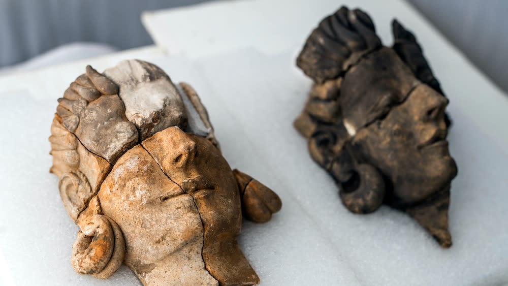  Two carved stone reliefs of human faces.  