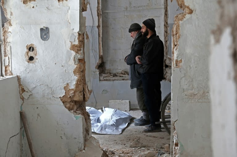 Syrian civil defence volunteers pray over the body of a victim who died in a building collapse following reported regime bombardment in Haza, in the besieged Eastern Ghouta region on February 26, 2018