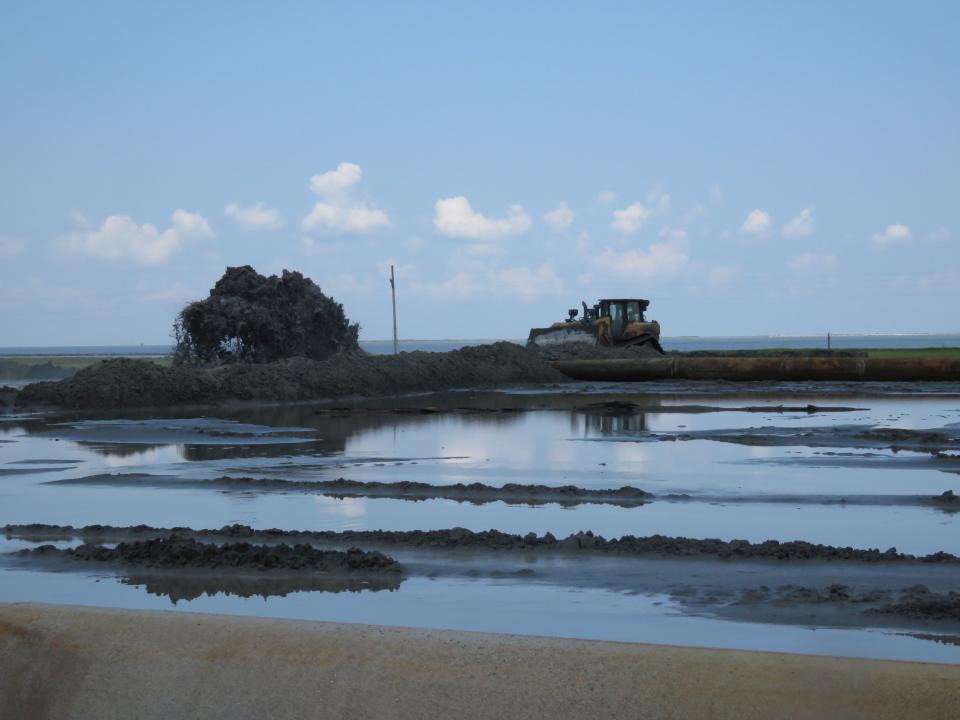 A bulldozer works near a 15-foot-high spray of sand and water being pumped from a dredge about five miles away to a Louisiana barrier island on Wednesday, July 28, 2021. Contractors are at work on a $102 million Louisiana Coastal Restoration and Protection Authority project to add about 400 acres of beach, dune and marshland to Grand Terre Island. Weather permitting, they hope to finish in November. (AP Photo/Janet McConnaughey)