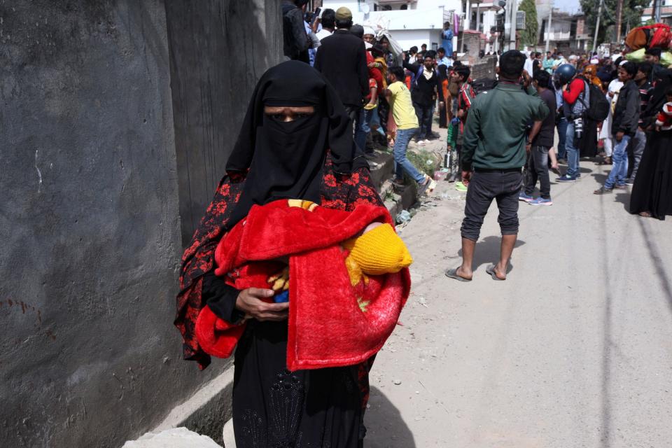 A Rohingya women, holding her child, leaves a Rohingya refugee camp.