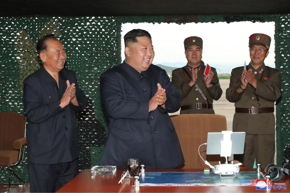 Kim Jong-un, centre, claps during the weapons test (Picture: AP)