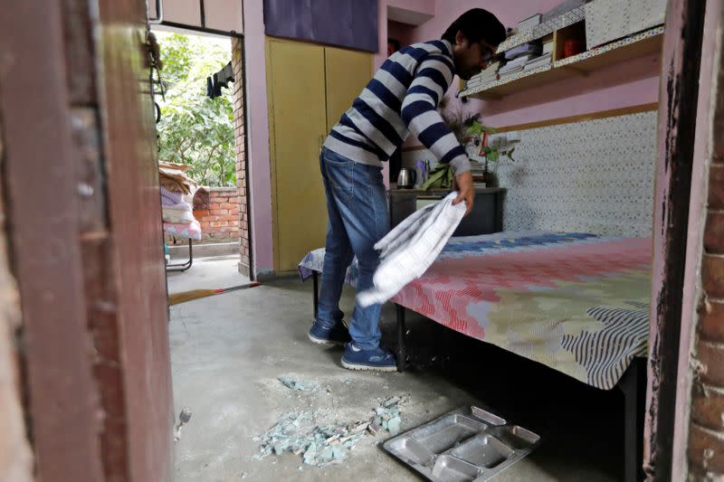 A student of Jawaharlal Nehru University cleans broken glasses from his hostel room after it was attacked by a mob on Sunday, in New Delhi