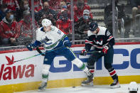 Vancouver Canucks defenseman Tyler Myers (57) and Washington Capitals right wing Brett Leason (49) look for the puck during the first period of an NHL hockey game against the Vancouver Canucks, Sunday, Jan. 16, 2022, in Washington. (AP Photo/Al Drago)