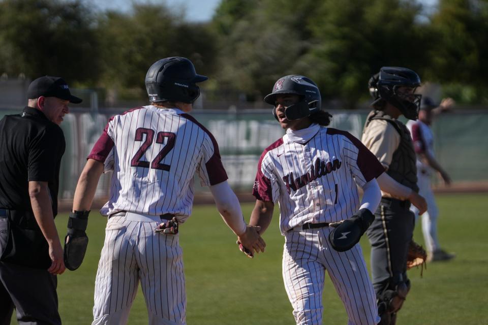 Hamilton High School’s Boston Kellner (22), left, and Jaylen Payne (1), right, celebrate after scoring against Basha High School during the third inning at Hamilton High School in Chandler on April 4, 2024.