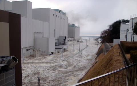 In this March 11, 2011 photo released Monday, April 11, 2011 by Tokyo Electric Power Co.,(TEPCO), the access road at the compound of the Fukushima Dai-ichi nuclear power plant is flooded as tsunami hit the facilit - Credit: AP