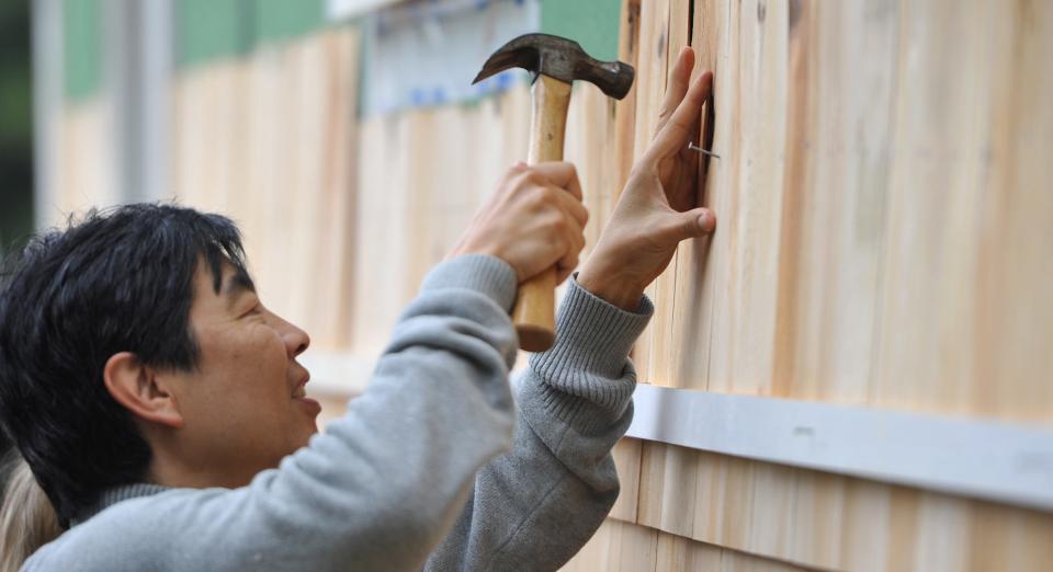 In this 2018 file photo, Cape Symphony conductor Jung-Ho Pak drives nails at a Habitat for Humanity site on Dickinson Drive in Marstons Mills. Members of the Cape Symphony joined volunteers to help shingle homes under construction there.