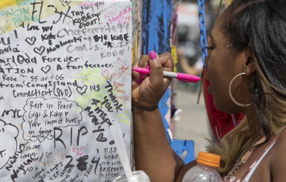 Diana Rutledge of Dayton, Ohio, writes a message on a mural on South La Brea honoring Kobe Bryant and his daughter Gianna