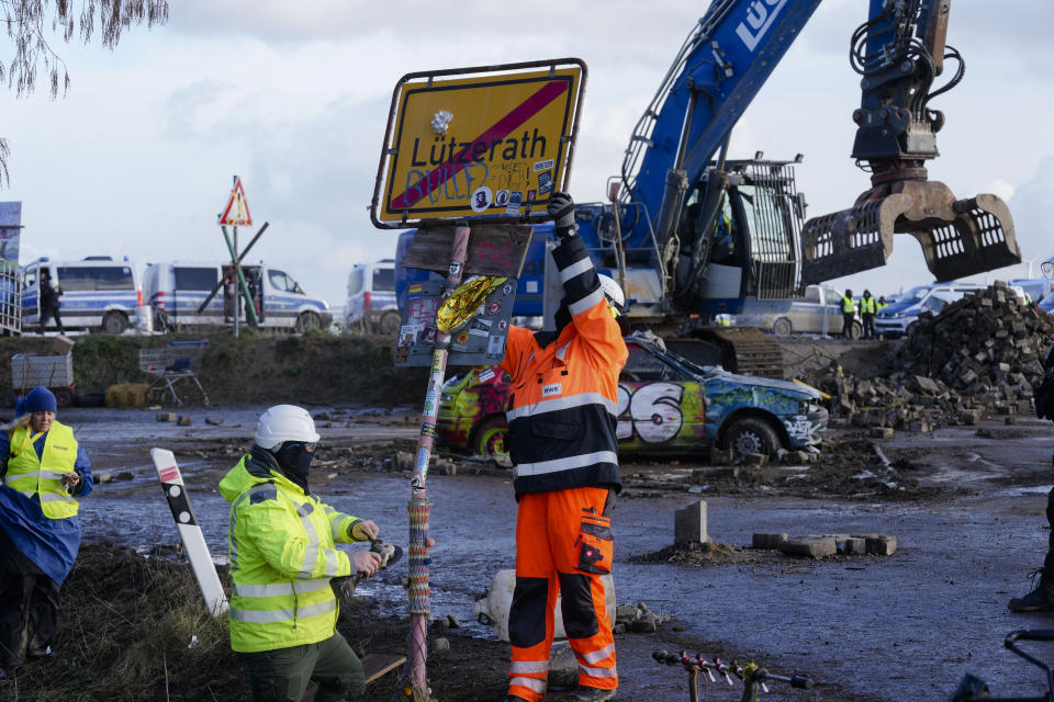 Workers of the German energy company RWE take down the place sign at the village Luetzerath near Erkelenz, Germany, Wednesday, Jan. 11, 2023. Police have entered the condemned village in, launching an effort to evict activists holed up at the site in an effort to prevent its demolition to make way for the expansion of a coal mine. (AP Photo/Michael Probst)