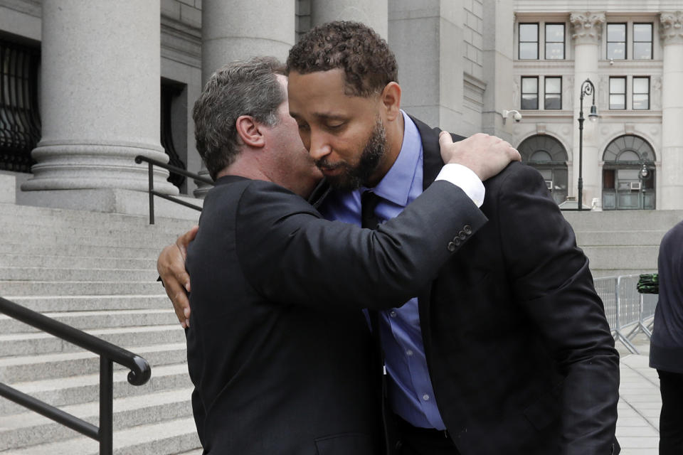 Former assistant basketball coach for the University of Southern California Tony Bland, right, is embraced by his attorney Jeffrey Lichtman as they leave federal court in New York, Wednesday, June 5, 2019. Bland was the first of four ex-coaches charged with crimes to plead guilty to bribery conspiracy. He was sentenced to 100 hours of community service and two years of probation. (AP Photo/Richard Drew)