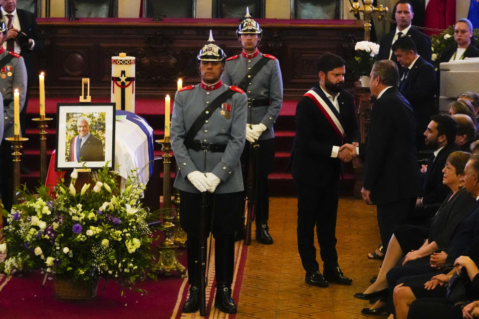 El presidente de Chile, Gabriel Boric, en el centro, le da la mano al exmandatario chileno Eduardo Frei junto al ataúd del fallecido presidente chileno Sebastián Piñera durante su velorio en el Congreso en Santiago, Chile, el viernes 9 de febrero de 2024. El dos veces expresidente murió el 6 de febrero en un accidente de helicóptero. Tenía 74 años. (AP Foto/Esteban Félix)