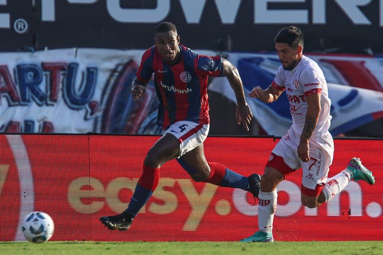 Romaña, el potente zaguero de San Lorenzo, corre por la pelota junto a Luna Diale