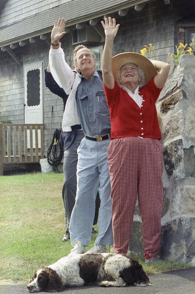 FILE - In this July 12, 1991, file photo, President George H.W. Bush and first lady Barbara Bush wave goodbye as Japanese Prime Minister Toshiki Kaifu leaves in a helicopter from their home at Walkers Point in Kennebunkport, Maine. The family dog Millie is in the foreground. The Bushes were married Jan. 6, 1945, and have had the longest marriage of any presidential couple in American history. (AP Photo/Dennis Cook, File)