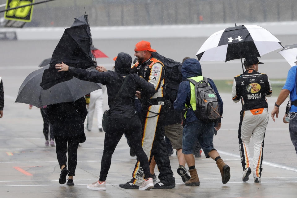 Noah Gragson, right, walks off of pit road with members of his crew after a rainstorm stopped a NASCAR Xfinity Series auto race at Kansas Speedway in Kansas City, Kan., Saturday, Sept. 10, 2022. Gragson won after the race was called. (AP Photo/Colin E. Braley)