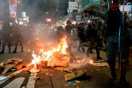 Riot police walk past a fire set by anti-extradition bill protesters during a protest at Prince Edward in Hong Kong