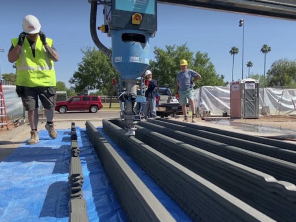 The home being 3D printed with machinery and a person