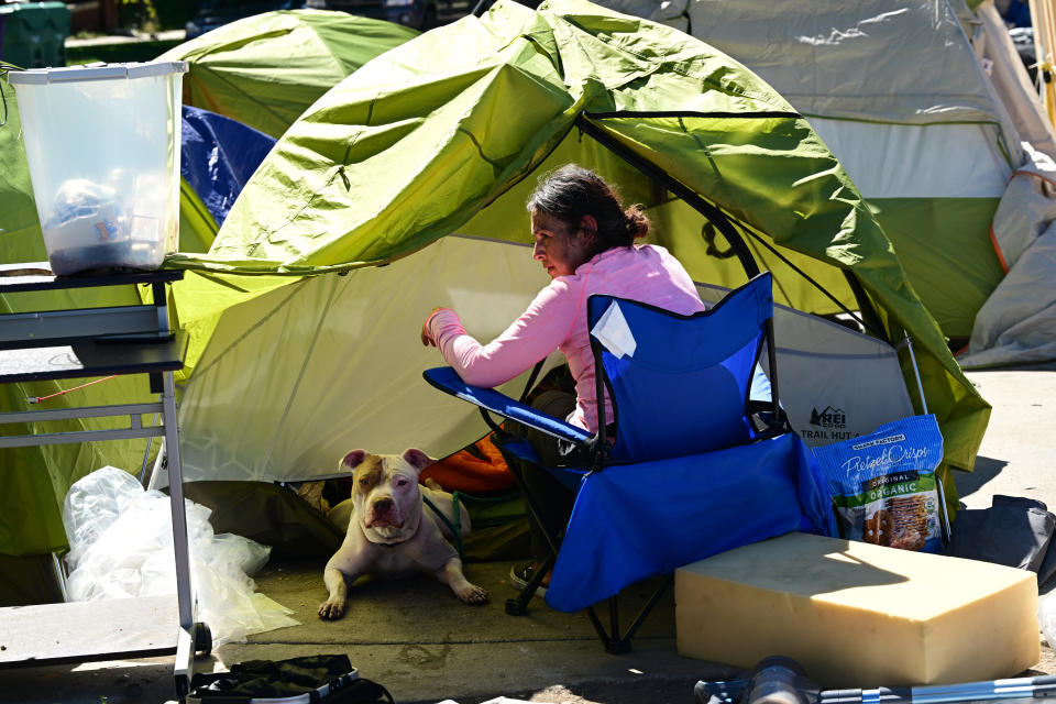 DENVER, CO - SEPTEMBER 25: Loraine Salis and her dog Ruger take a break from  packing up their belongings at the encampment along North Logan street and E. Eighth ave on September 25, 2023 in Denver,  Colorado. Under the guidance of newly elected Mayor Michael Johnston, the city of Denver is doing sweeps of  homeless encampments in Denver but instead of forcing the unhoused to move they are offering the residents in the encampments someplace else to go. In this case a hotel. Denver city crews and outreach workers helped those living in the large encampment at East Eighth Ave and Logan streets to pack up their belongings. Crews gave large bags to people who were able to pack their personal items onto trucks that then delivered them to the hotel. 72 people were given rooms in newly bought hotels that have been converted into a non-congregate homeless shelters. Buses transported the people transitioning from the camp to the hotel shelter. People were able to take all of their belongings and their pets. Officials with the city say that these hotels and micro-communities aim to provide support and help people transition to permanent housing in a 6-12 month timeframe.  (Photo by Helen H. Richardson/MediaNews Group/The Denver Post via Getty Images)