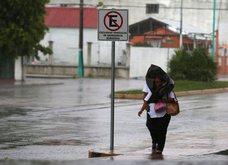 A woman uses a plastic bag to shield from the rain as Hurricane Earl approaches the beach resort of Chetumal, Mexico, August 3, 2016. REUTERS/Lorenzo Hernandez