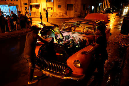 Self-employed Carlos Ochoa (C) fixes a vintage car in Havana, Cuba, April 13, 2018. REUTERS/Alexandre Meneghini