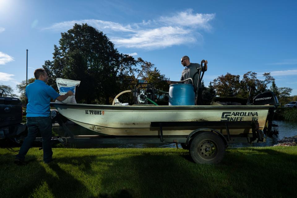 McCloud Aquatics President T.J. McCloud (left) and Chris Hoffman prepare a bentonite clay solution to treat algae growth in a pond in Arlington Heights, Illinois, on Tuesday, October 19, 2021.