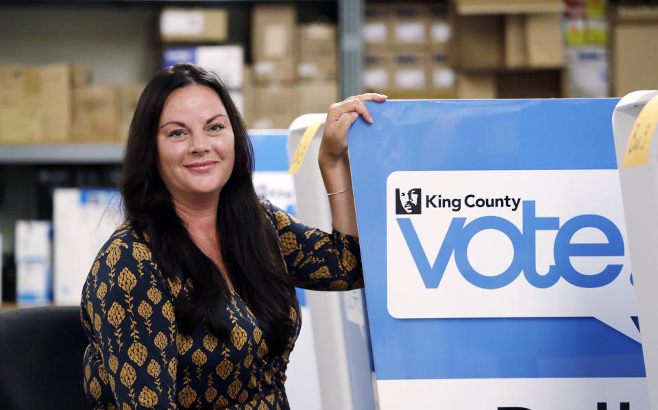 FILE - Julie Wise, King County's elections director, poses for a photo alongside a ballot drop box, Oct. 9, 2018, at the King County Elections office in Renton, Wash. While her workers were counting ballots for primary elections last August, Wise had to order an evacuation of their building after receiving a suspicious envelope that turned out to contain trace amounts of fentanyl. Threatening letters sent to local election offices in at least five states, some including fentanyl, are the latest concern for local election workers around the country, who have faced harassment and even death threats since the 2020 presidential election (AP Photo/Elaine Thompson, File)