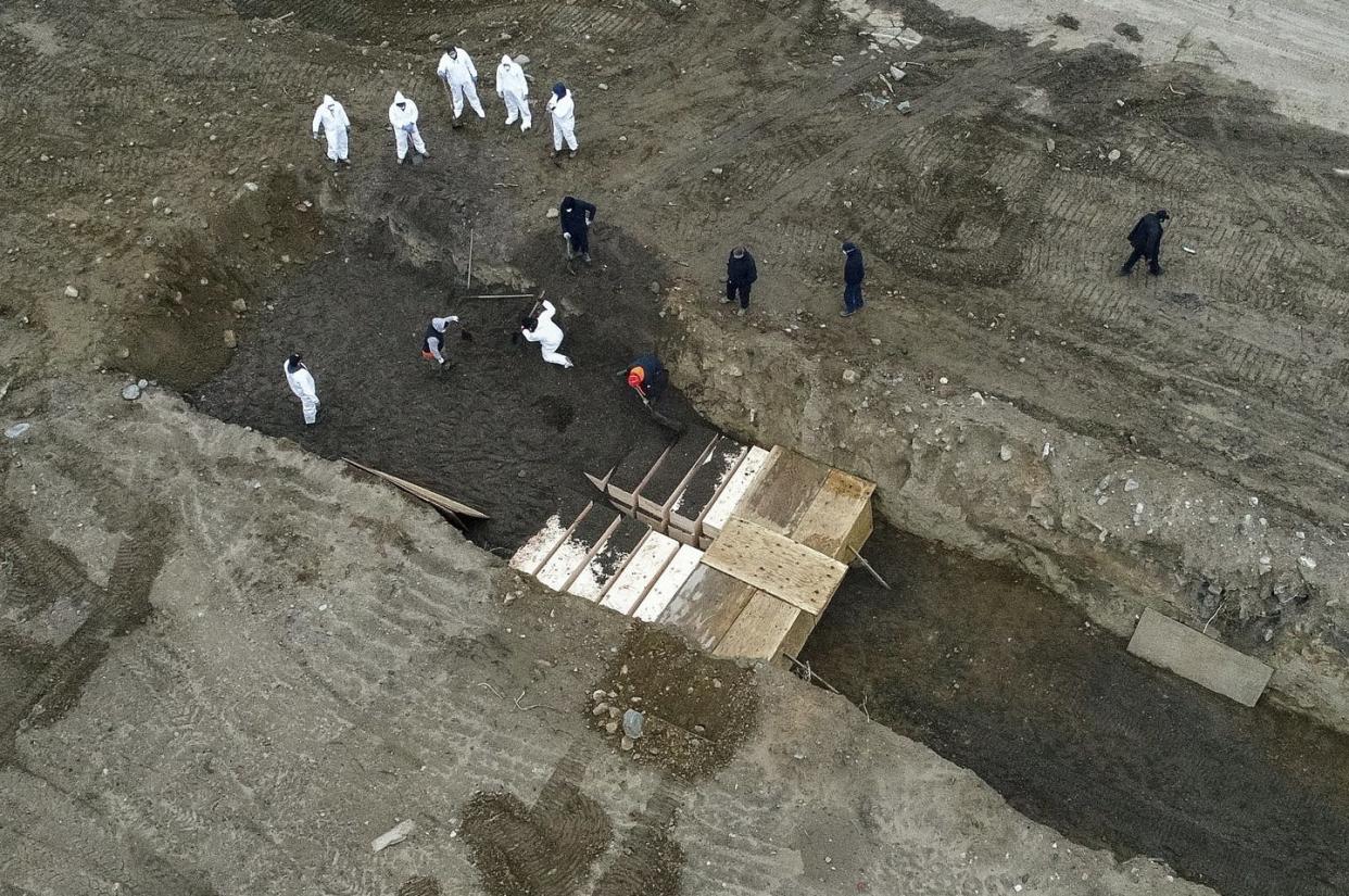 <span class="caption">Workers wearing personal protective equipment bury bodies in a trench on Hart Island in New York.</span> <span class="attribution"><a class="link " href="http://www.apimages.com/metadata/Index/Virus-Outbreak-New-York/b223d9e3c93e442a980116ea1f335d86/12/0" rel="nofollow noopener" target="_blank" data-ylk="slk:John Minchillo/AP Photo;elm:context_link;itc:0;sec:content-canvas">John Minchillo/AP Photo</a></span>