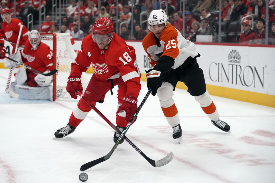 Detroit Red Wings center Andrew Copp (18) and Philadelphia Flyers center Ryan Poehling (25) reach for the puck during the first period of an NHL hockey game, Thursday, Jan. 25, 2024, in Detroit. (AP Photo/Carlos Osorio)