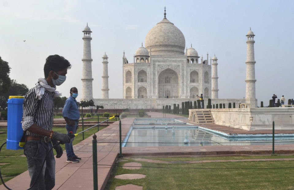 FILE- A man disinfects the premises of the Taj Mahal monument that was reopened after being closed for more than six months due to the coronavirus pandemic in Agra, India, Monday, Sept.21, 2020. After nearly 18 months, India Monday allowed fully vaccinated foreign tourists traveling on regular flights to enter the country in the latest easing of its coronavirus restrictions as infections fall and vaccinations pick up. (AP Photo/Pawan Sharma, file)