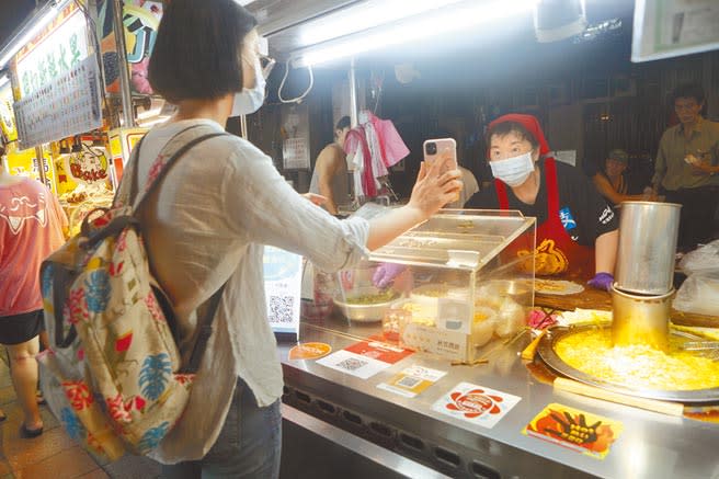 行政院7月15日將推出振興三倍券，中華郵政公司預估會有40％民眾、約1000萬人到郵局領券，將對郵局業務帶來龐大壓力，圖為一位民眾使用電子支付向北市寧夏夜市的攤商成功付款。（本報資料照片）