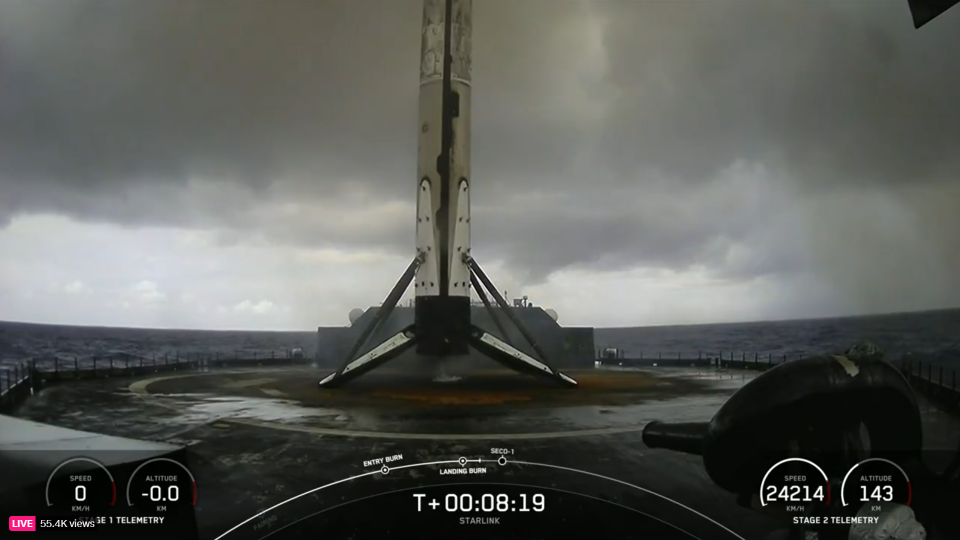 A new SpaceX Falcon 9 rockets sits on a drone ship landing pad in the Atlantic Ocean under gray clouds.