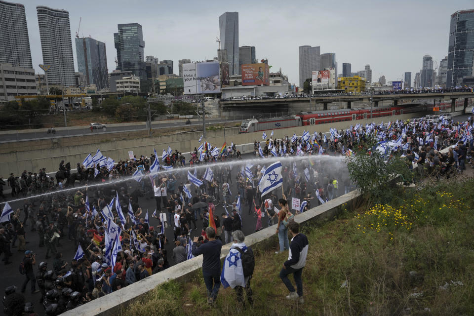 Israeli police use a water cannon to disperse Israelis blocking the freeway during a protest against plans by Prime Minister Benjamin Netanyahu's government to overhaul the judicial system in Tel Aviv, Israel, Thursday, March 23, 2023. (AP Photo/Oded Balilty)