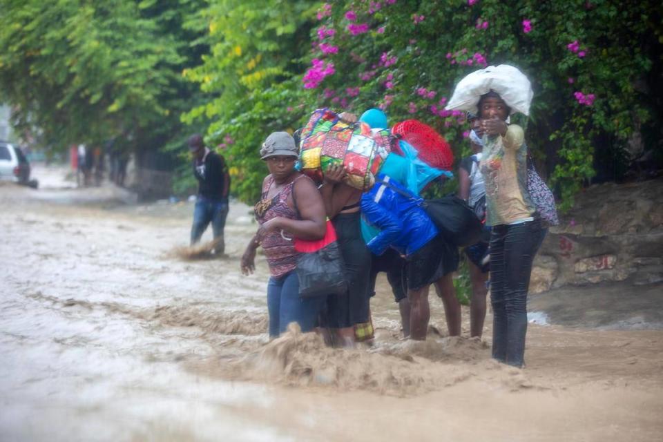 People cross a flooded street during the passing of Tropical Storm Laura in Port-au-Prince, Haiti, Sunday, Aug. 23, 2020.