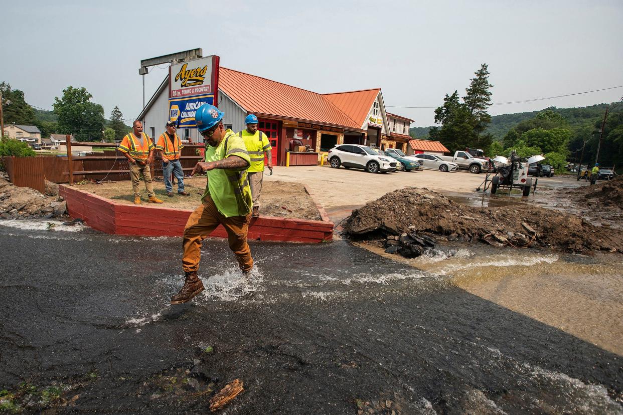 Workers cross roadway impacted by recent storms and flooding, Monday, July 17, 2023, in Belvidere, New Jersey. (AP Photo/Eduardo Munoz Alvarez)