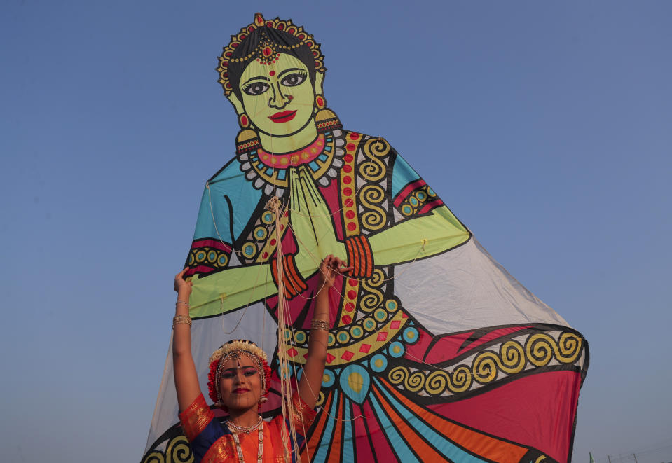 In this Jan. 13, 2020, photo, an Indian woman poses with a kite during the International Kite Festival in Hyderabad, India. The three-day kite festival was organized by Telangana State Tourism Department, bringing together international teams of professional kite-flyers, along with thousands of kite-enthusiasts from around the city. (AP Photo/Mahesh Kumar A., File)