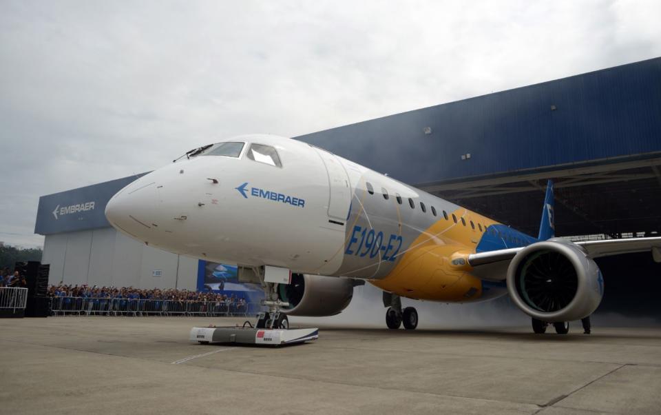 An Embraer E190-E2 jet parked in front of a hangar.