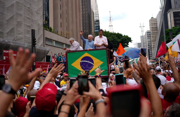 El expresidente de Brasil Luiz Inacio Lula da Silva saluda a sus seguidores acompañado por el expresidente de Uruguay José "Pepe" Mujica y el candidato a gobernador de San Pablo, Fernando Haddad, durante un evento de campaña en la Avenida Paulista