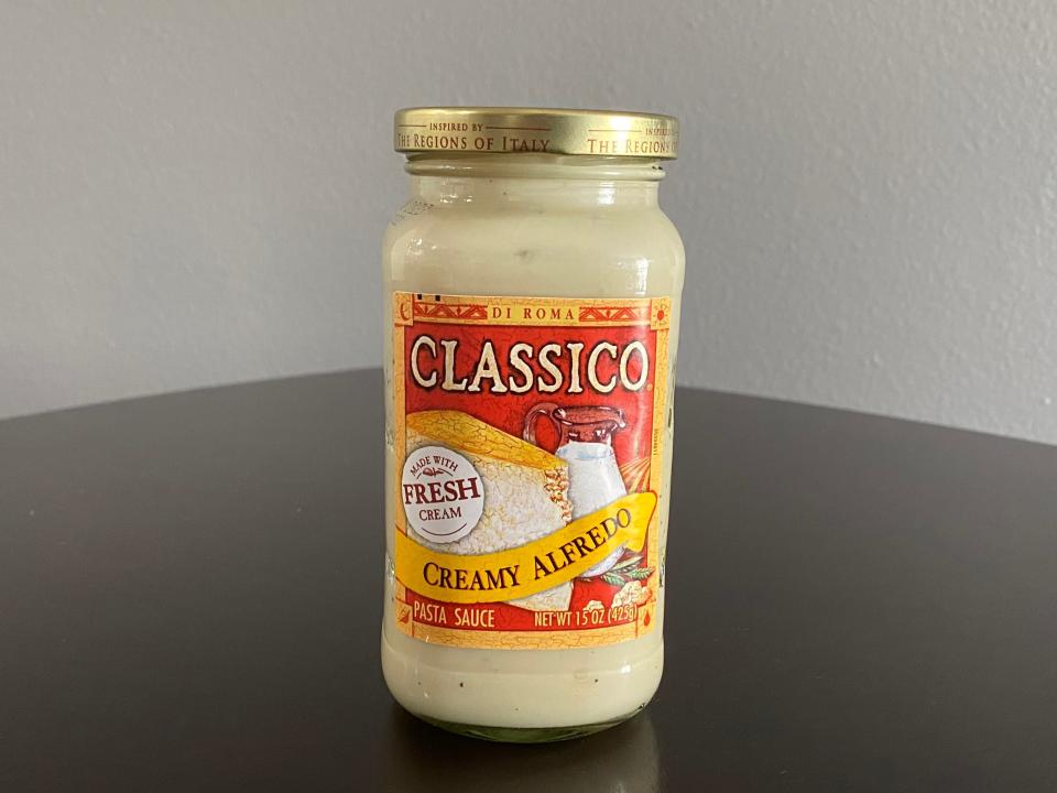 A jar of Classico Alfredo sauce on a black table