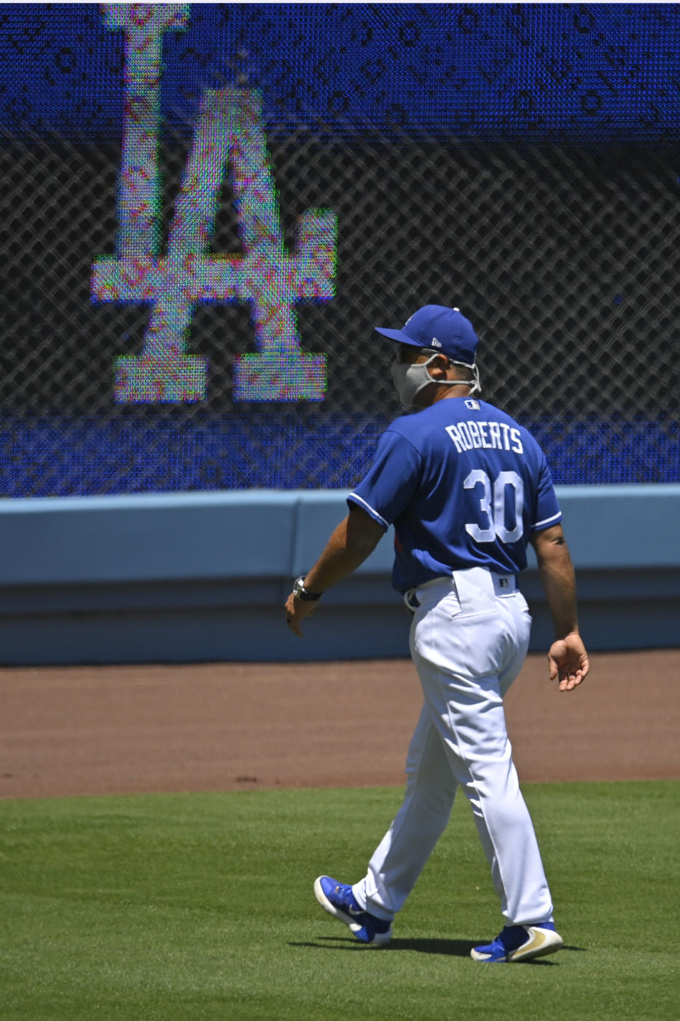 Los Angeles Dodgers manager Dave Roberts walks in the outfield during the restart of spring training Friday, July 3, 2020, in Los Angeles. (AP Photo/Mark J. Terrill)a