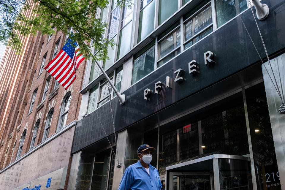 Pedestrians wearing a protective mask walks past Pfizer Inc. headquarters on July 22, 2020 in New York City. (Photo by Jeenah Moon/Getty Images)