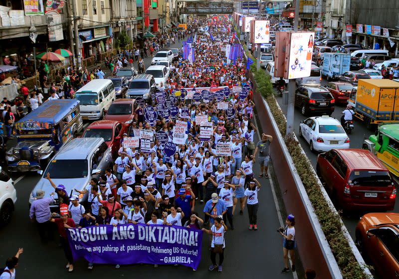 Women's rights activists display a streamer that reads "Down with Dictatorship" as they march along a busy street during a celebration of the International Women's Day in Quiapo city, Metro Manila