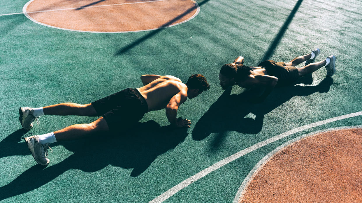  Two men perform push-ups on a basketball court 