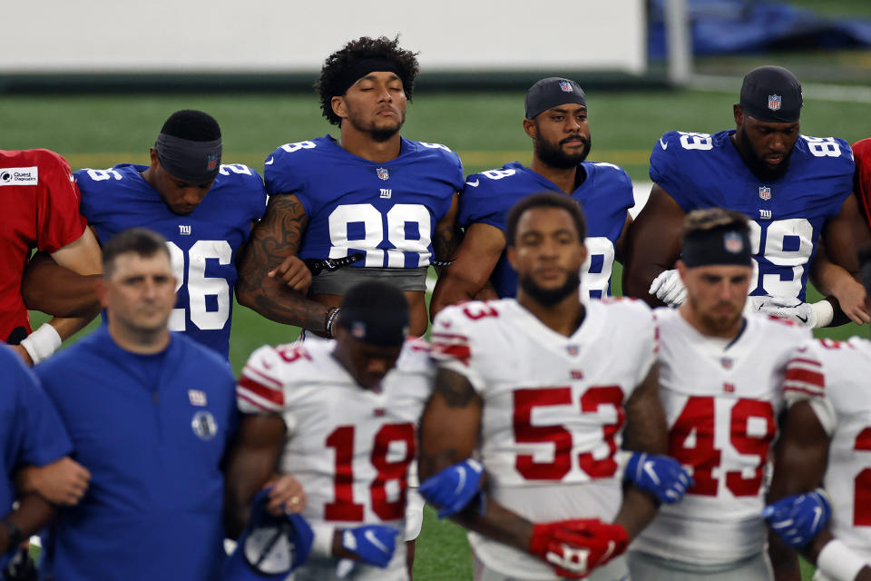 New York Giants tight end Evan Engram (88) and Saquon Barkley (26) stand with linked arms with teammates to make a social injustice statement prior to their scrimmage at the NFL football team's training camp in East Rutherford, N.J., Friday, Aug. 28, 2020. (AP Photo/Adam Hunger)