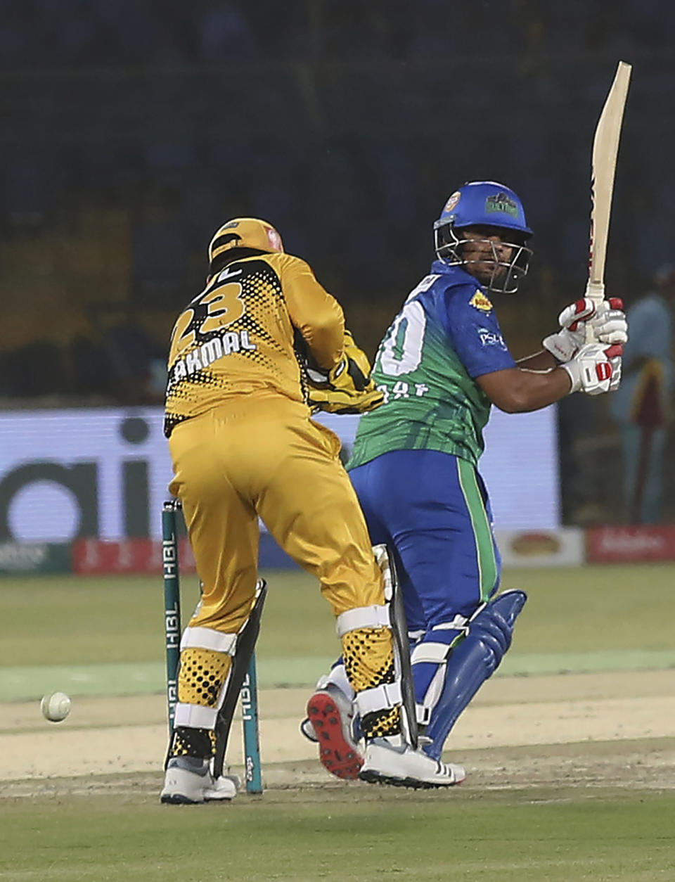 Zeeshan Ashraf of Multan Sultans who scores 50 off 35 balls, hits a boundary as Peshawar Zalimi's Kamran Akmal looks on during the Pakistan Super League match at the National Stadium in Karachi, Pakistan, Friday, March 13, 2020. (AP Photo/Fareed Khan)