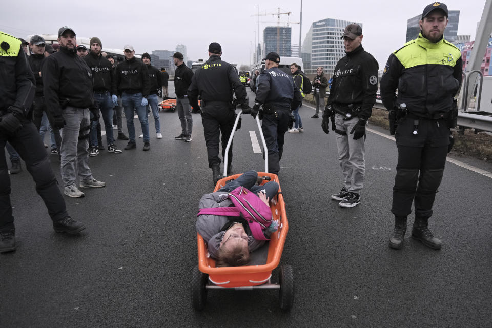 Police take away a climate activist detained for blocking the main highway around Amsterdam near the former headquarters of a ING bank to protest its financing of fossil fuels, Saturday, Dec. 30, 2023. Protestors walked onto the road at midday, snarling traffic around the Dutch capital in the latest road blockade organized by the Dutch branch of Extinction Rebellion. (AP Photo/Patrick Post)