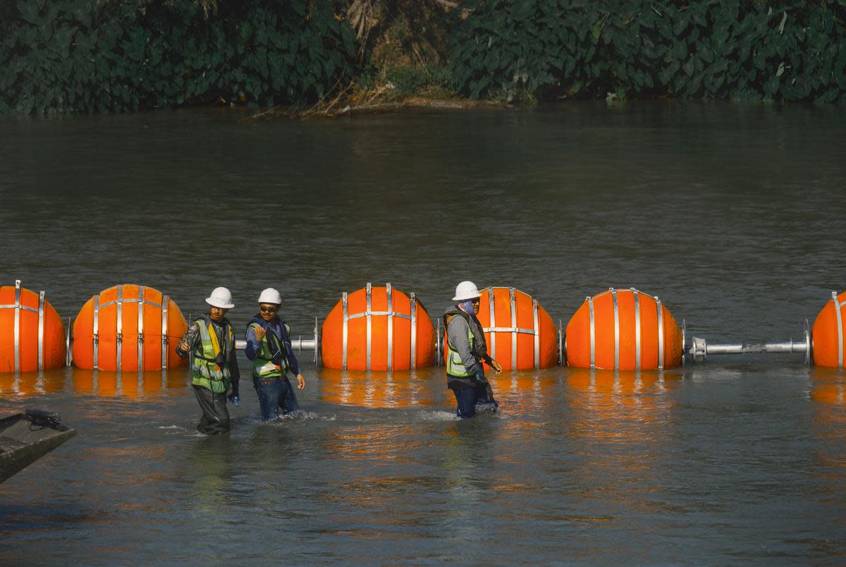 Workers construct a string of buoys which is being deployed to prevent migrants from swimming across the Rio Grande in Eagle Pass on July 14, 2023.