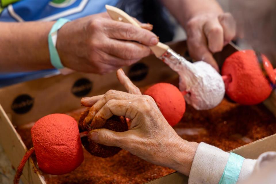 Two volunteers apply cuttings of safflower on an ornamental piece for a Rose Parade float in Irwindale.