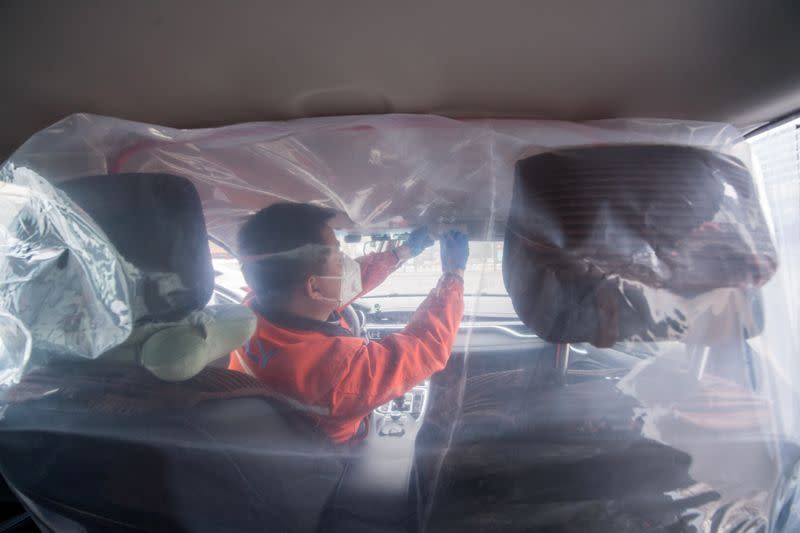 Un trabajador instala una película plástica para separar los asientos delanteros de los traseros, en el interior de un vehículo para un servicio de granallado de coches mientras el país es golpeado por un brote del novedoso coronavirus, en Taiyuan, provincia de Shanxi, China 14 de febrero de 2020