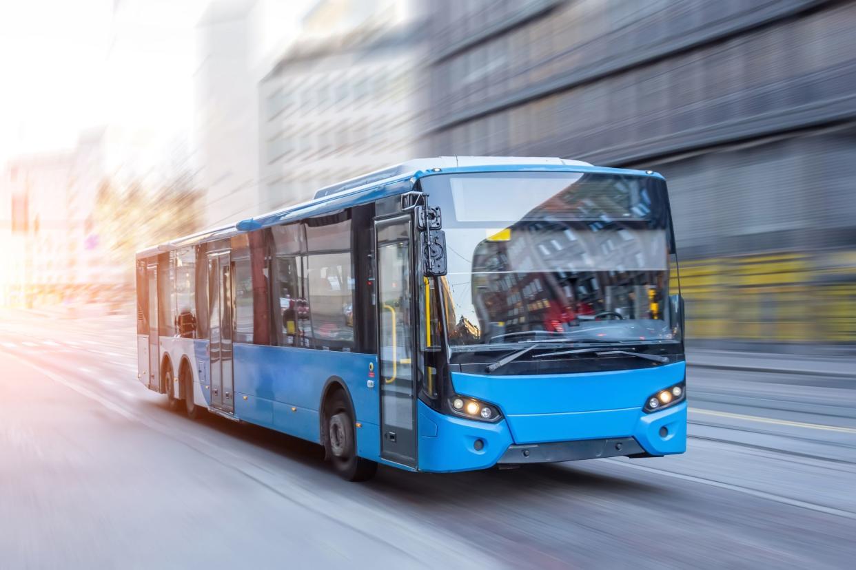 Blue bus moving on the road in city in early morning